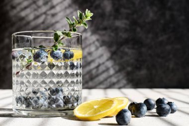 Fresh summer drink blueberry mojito or blueberry icy lemonade with lemon slices, blueberries, ice and thyme.