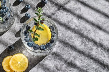 Fresh summer drink blueberry mojito or blueberry icy lemonade with lemon slices, blueberries, ice and thyme.