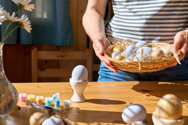 Paskalya süslemelerini hazırlayan kadının elleri renkli paskalya yumurtalarıyla dolu sepeti tutuyor..