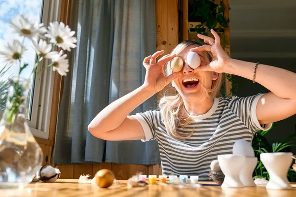 stock image Smiling woman preparing easter decoration at home, painting colorful easter eggs and coloring egg cups.