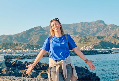 Mutlu turist kadın deniz kenarında özgürlüğün tadını çıkarıyor. Dişi gezgin sakin doğada dinleniyor. Akıl sağlığı, sağlık, macera yolculuğu ve sağlıklı yaşam tarzı..