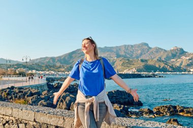 Mutlu turist kadın deniz kenarında özgürlüğün tadını çıkarıyor. Dişi gezgin sakin doğada dinleniyor. Akıl sağlığı, sağlık, macera yolculuğu ve sağlıklı yaşam tarzı..