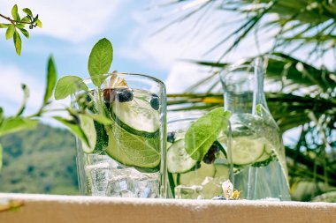 Serinletici yaz içeceği. Bahçedeki masada salatalık, adaçayı, salatalık ve limon çiçeği ile karıştırılmış su. Taze, sağlıklı, soğuk detoks içeceği. Spor içeceği..