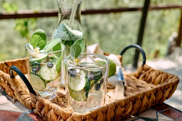 stock image Refreshing summer drink - cucumber infused water with ice, sage, cucumber and lemon blossom on the table in the garden. Fresh healthy cold detox beverage. Fitness drink.