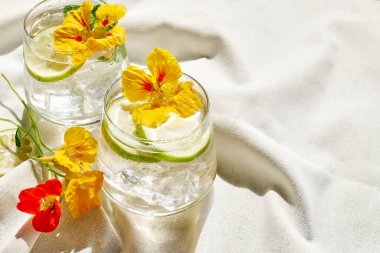 Iced lemonade with edible nasturtium flowers, lime and mint leav clipart