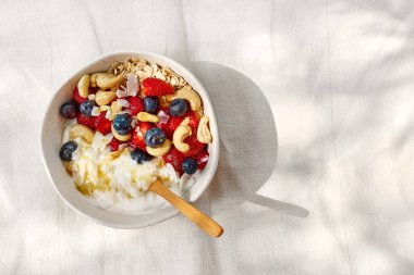 Çilekli, yaban mersinli ve beyaz kaseli hindistancevizli yoğurt taneciği. Sağlıklı kahvaltı, vejetaryen yemeği, diyet, kilo kaybı, sağlıklı beslenme.