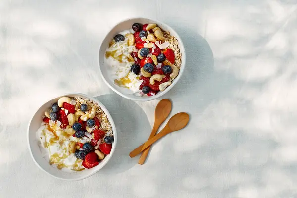 Coconut yogurt granola with strawberry, blueberry and cashew in white bowl. Concept of healthy breakfast, vegetarian meal, dieting, weight loss, healthy eating.