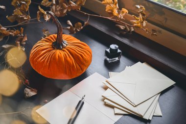 Balkabağı, kâğıt yaprakları, dolmakalem ve yanan mumla dolu sakin bir sonbahar hayatı. Sonbahar evi dekorasyonu. Sıcak sonbahar havası.