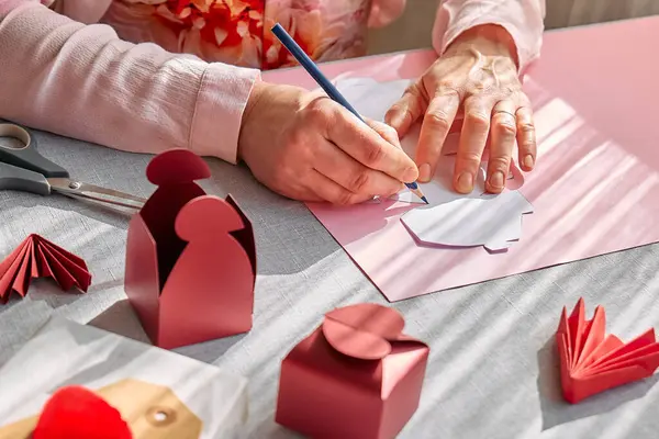 Paper craft diy. Woman\'s hands making handmade heart shaped gift box for Valentines day, birthday, Mothers day, wedding.