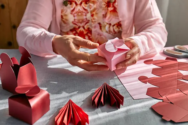 Paper craft diy. Woman\'s hands making handmade heart shaped gift box for Valentines day, birthday, Mothers day, wedding.