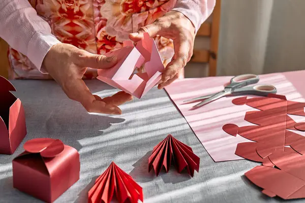 Paper craft diy. Woman's hands making handmade heart shaped gift box for Valentines day, birthday, Mothers day, wedding.