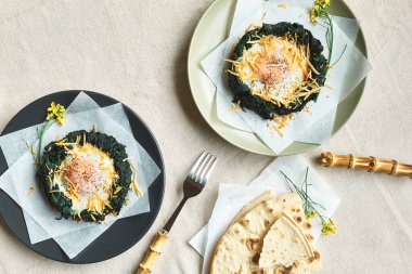 Paskalya kahvaltısı fikri. Fırınlanmış ıspanak yumurtası yuvaları rendelenmiş peynir ve karabiberle süslenmiş. Şenlikli yemekler. Çocuklar için komik sağlıklı yiyecekler.