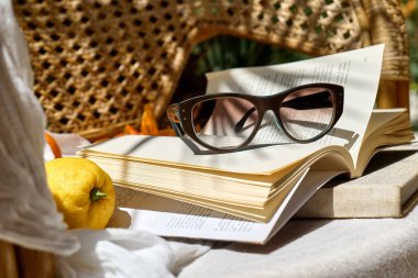 Yaz tatilinde okumak. Kitap, taze içecek, güneş gözlüğü ve şapka tropik bahçede hasır sandalyede beyaz plaj battaniyesinde. Yaz mevsimi havası.