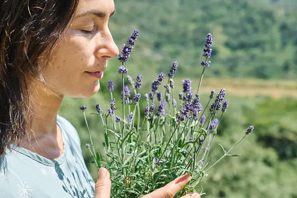 Kadın, kokulu lavanta çiçeklerinin kokusunu içine çekiyor. Doğal bitkisel tedavi yöntemleri. Alternatif tıp. Lavanta yağı. Aromaterapi.