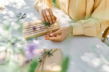 El yapımı hediye paketi yapan kadın geri dönüştürülmüş kağıt ve masada keten masa örtüsüyle kurutulmuş lavanta çiçekleri yapıyor. Doğal estetik..