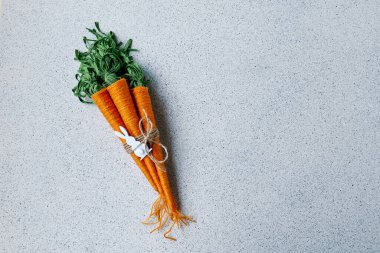 Gri arka planda yün iplik havuçları. Paskalya için minimalist dekor. DIY el yapımı el işi dekorasyonu.