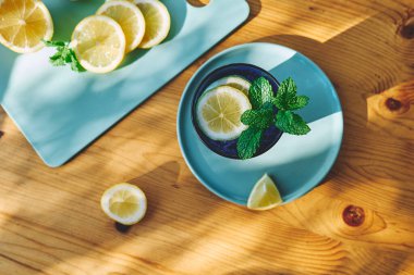 Tahta masada nane, buz ve limon dilimleri ile ferahlatıcı yaz limonata içeceği. Taze, sağlıklı, soğuk limon suyu. Limonla doldurulmuş su.