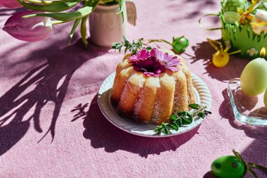 Paskalya pastası, masaya şeker ve papatya çiçekleri ile süslenmiş paskalya yumurtaları ve pembe masa örtüsünün üzerinde lalelerle. Geleneksel paskalya pastası ya da üzerine tatlı ekmek. Paskalya hediyesi.