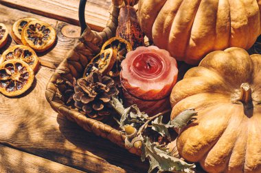 Cozy warm autumn composition with burning candle and pumpkins on knitted woolen plaid. Autumn home decor. Fall mood. Thanksgiving. Halloween.