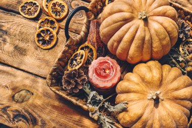 Cozy warm autumn composition with burning candle and pumpkins on knitted woolen plaid. Autumn home decor. Fall mood. Thanksgiving. Halloween.