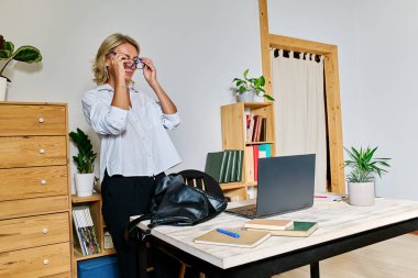 Sarı saçlı iş kadını iş yerine geliyor ve gözlük takıyor.