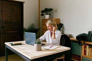 Ofisteki dizüstü bilgisayara odaklanmış sarı saçlı iş kadını.