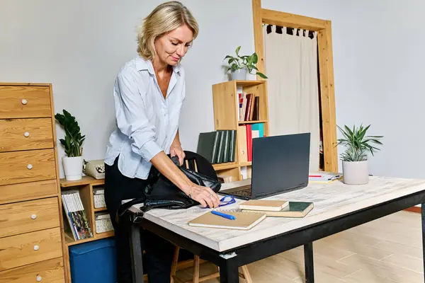 Sarı saçlı iş kadını iş yerine geliyor ve çantasını masanın üstüne boşaltıyor.