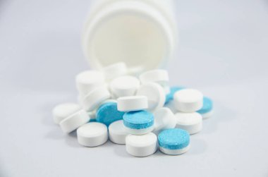 white and blue pill on white blackground with bottle