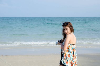 asian women hold camera on beach