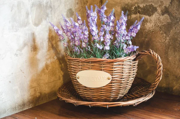 violet plastic flowers in wooden pot