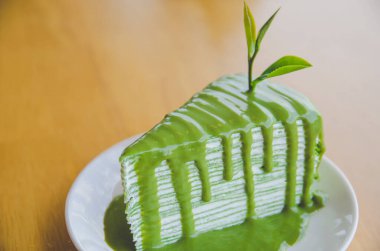 green tea crepe cake on white plate on wooden table