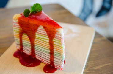close up of rainbow crepe cake on wooden plate