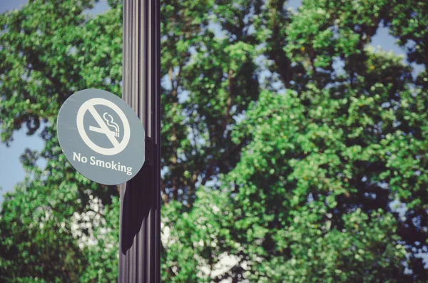 No smoking sign of pole with tree background