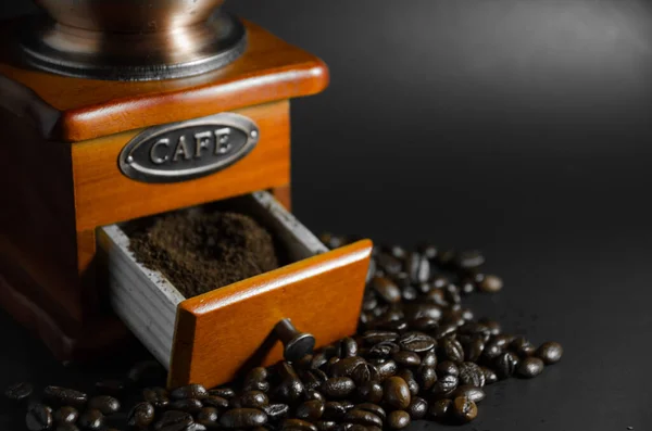 ground coffee in coffee grinder with coffee beans on black background