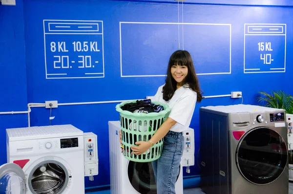 Asian girl is holding  basket in laundry shop with smile face