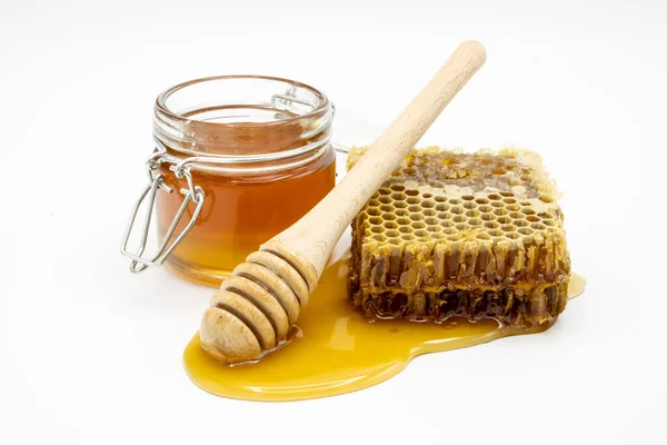 stock image jar of honey next to honeycomb and honey dipper isolated on white background