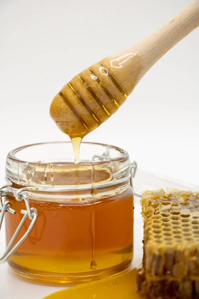 蜂窝和蜂蜜棒旁边的蜂蜜罐 — 图库照片