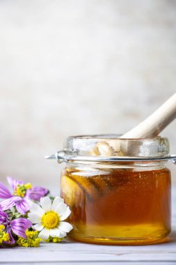 Çiçeklerin yanında bal kavanozu.