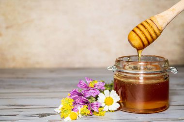Çiçeklerin yanında bal kavanozu.