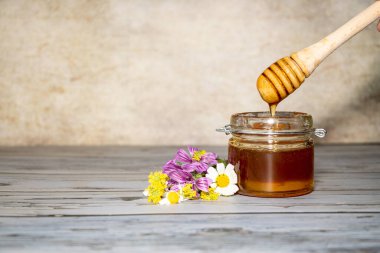 Çiçeklerin yanında bal kavanozu.