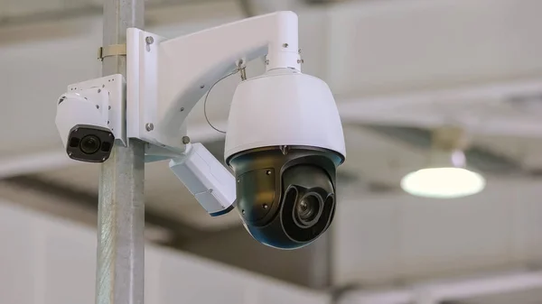 Rotating black surveillance control camera indoors. Public safety concept.