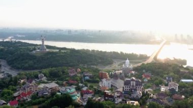 Nehir ve akşam günbatımından oluşan küçük bir hava manzarası. Anavatan heykeli ve ağaçlar.