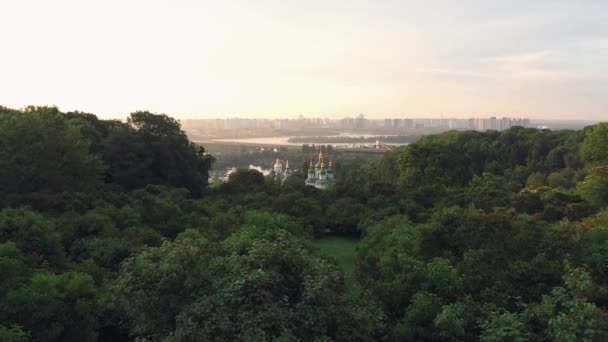 緑の木々に囲まれた正統派教会の風景 夏にウクライナのキエフPechersk Lavra 夕日の空 — ストック動画