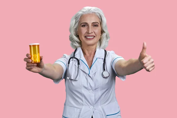 Portret Szczęśliwej Starszej Pani Doktor Pokazuje Żółtą Butelkę Leku Kciuk — Zdjęcie stockowe