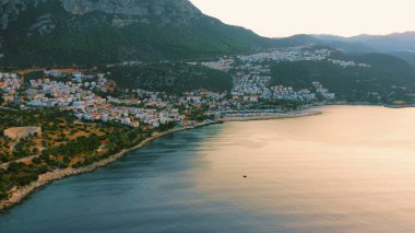 Dağlar ve turuncu gün batımı gökyüzü ile inanılmaz bir manzara. Akşamları tatil köyünün panoraması. Resimli doğa manzarası.