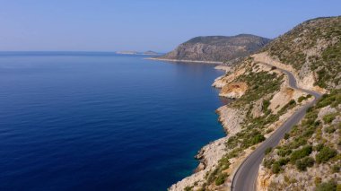 Turkuaz deniz ya da okyanus kıyısındaki dağ yolunun insansız hava aracının muhteşem manzarası. Gökten görkemli doğa manzarası.