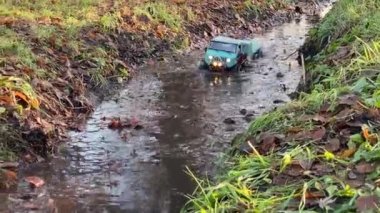 Kyiv, Ukrayna - 26.09.2021: Flatbed çekici oyuncak orman birikintisi boyunca gidiyor. RC aracı sağanak yağmurdan sonra suda hareket ediyor.