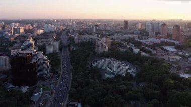 Araç trafiğiyle şehir manzarası. Birçok bina ve ağaç.