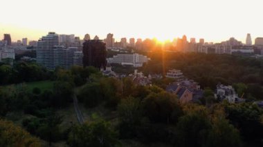 Şehrin panoramik manzarası. Parlak akşam güneşiyle birlikte. Yeşil ağaçlar ve binalar.