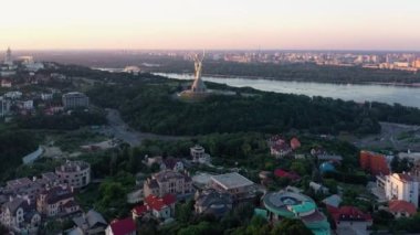 Nehir ve anıtla akşam şehir manzarası. Kiev şehrinde insansız hava aracı görüntüsü.